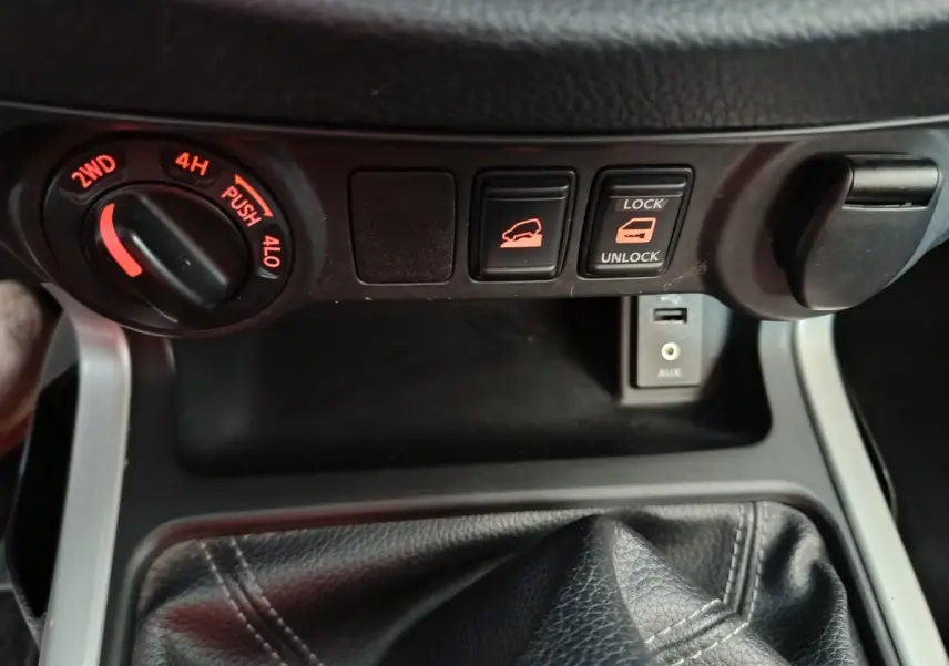 Gros plan sur la console centrale du Nissan Navara 2018, montrant les commandes de traction, verrouillage de benne et prise USB.