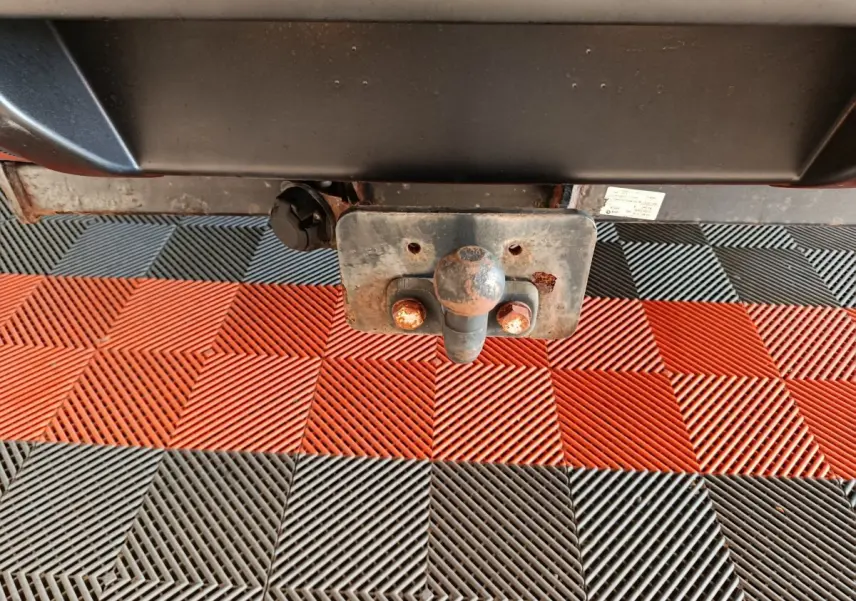 Gros plan sur l'attelage rouillé du Nissan Navara gris clair, vue centrée sous l'arrière du véhicule.