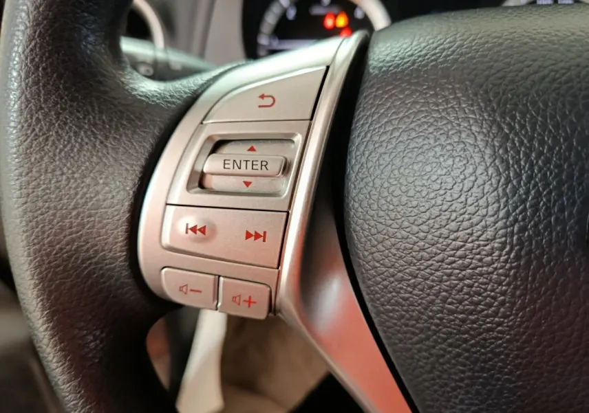 Gros plan sur le volant noir multifonctions du Nissan Navara 2018, avec boutons de contrôle argentés et affichage partiel du tableau de bord.