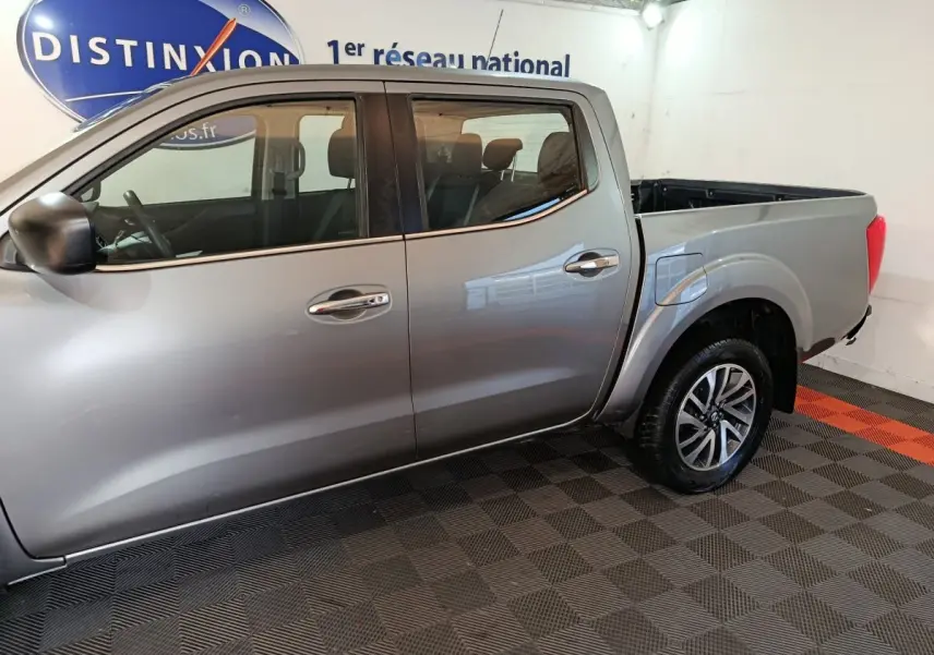 Vue latérale côté gauche d'un Nissan Navara Double-Cab gris clair avec benne pick-up et jantes alliage.