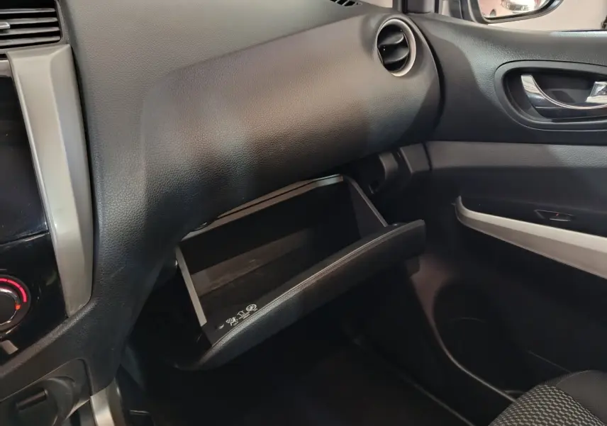 Vue intérieure du tableau de bord côté passager du Nissan Navara gris clair, avec boîte à gants ouverte et garnitures noires.