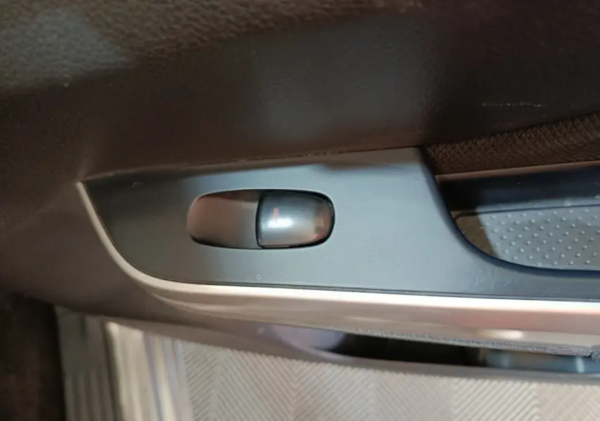 Gros plan sur le bouton de verrouillage de porte intérieur noir dans un Nissan Navara gris clair, version Double-Cab 2018.