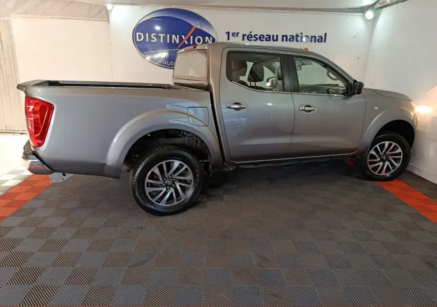 Vue de profil côté droit d'un Nissan Navara Double-Cab gris clair 2018 avec benne pick-up et jantes alliage.