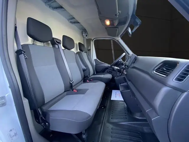 Vue intérieure côté conducteur du Renault Master blanc 2022, montrant les sièges gris et la planche de bord fonctionnelle.