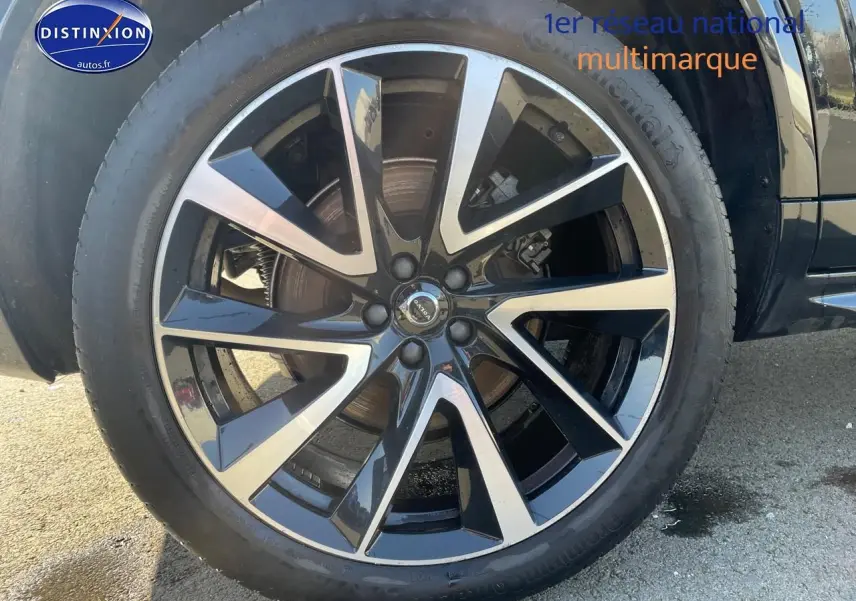 Gros plan sur la jante alu noire et argentée du côté gauche d'un Volvo XC90 noir 2023.