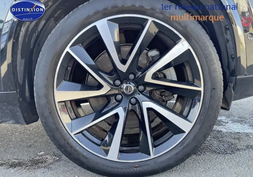 Gros plan sur la jante alu noire et argentée du côté gauche d'un Volvo XC90 noir 2023.