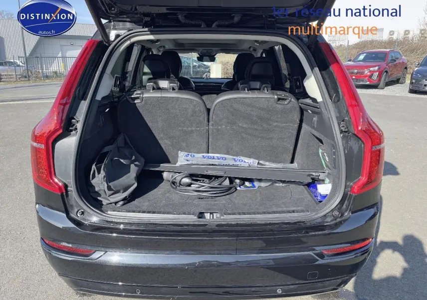 Coffre ouvert vu de l'arrière d'un Volvo XC90 noir avec sièges rabattus et accessoires à l'intérieur.