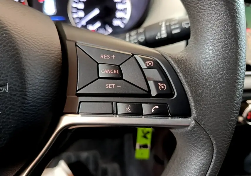 Gros plan sur le côté droit du volant noir de la Nissan Micra 2020 avec commandes de régulateur de vitesse et téléphone.
