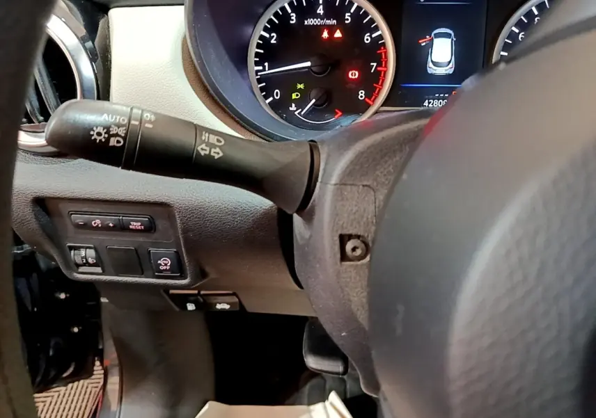 Vue rapprochée du tableau de bord et du volant de la Nissan Micra gris foncé, avec compte-tours et commandes lumineuses visibles.