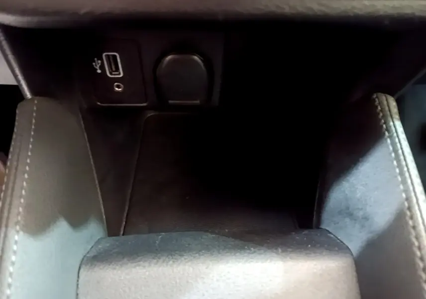 Gros plan intérieur sur la console centrale noire de la Nissan Micra IG-T 100 Business Edition avec prise USB et prise 12V.