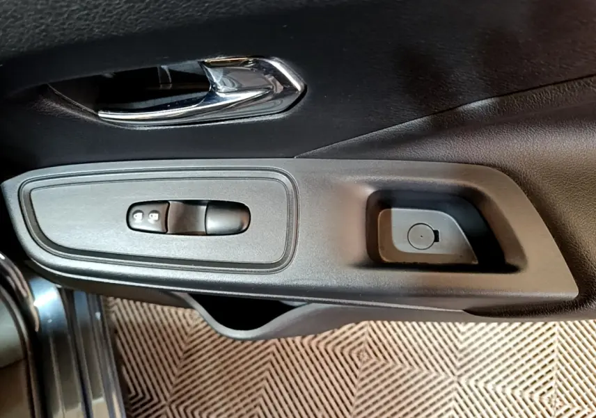 Gros plan sur la poignée intérieure et les commandes de verrouillage de porte côté conducteur d'une Nissan Micra gris foncé.