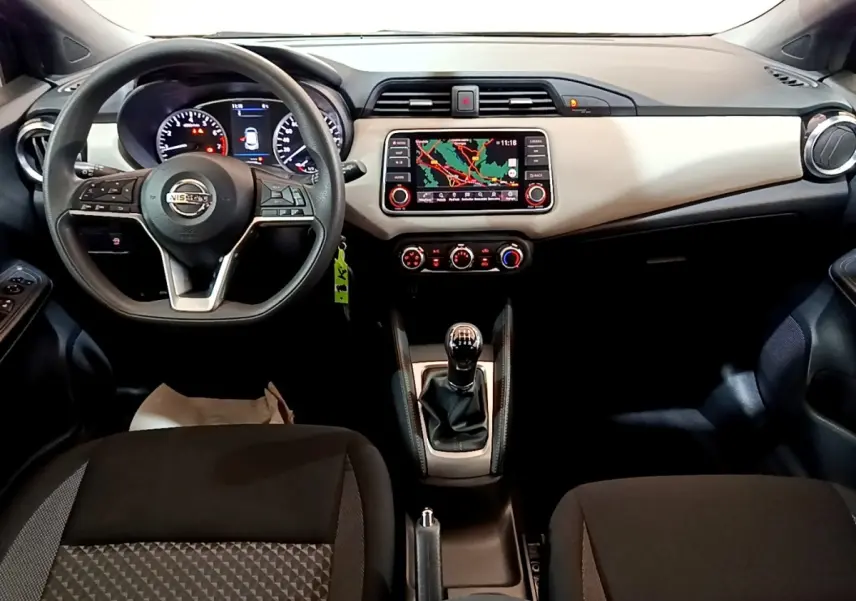 Vue intérieure frontale du tableau de bord et volant noir de la Nissan Micra IG-T 100 Business Edition avec écran tactile et levier de vitesses manuel.