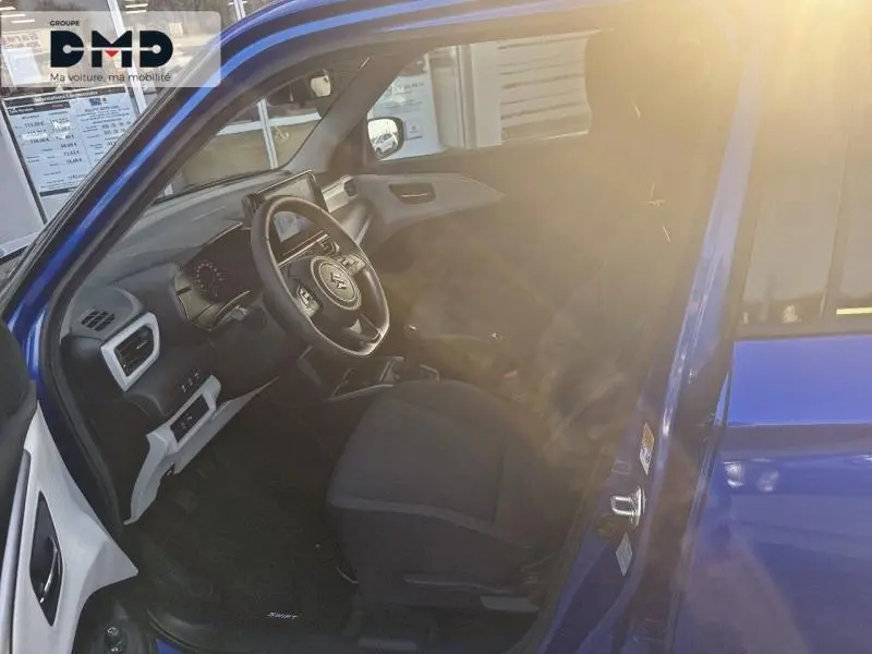 Intérieur avant droit de la Suzuki Swift 1.2 Hybrid bleu Frontier, volant cuir multifonction et sièges tissu noirs.