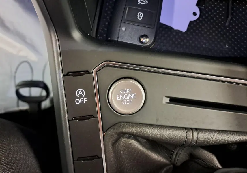 Gros plan sur la console centrale noire avec bouton Start Engine Stop et commande auto start/stop du Volkswagen Taigo 2025.
