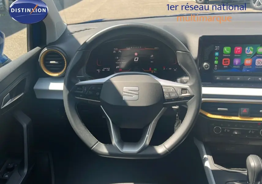Vue intérieure centrée sur le volant du SEAT Arona 2025, avec tableau de bord numérique et écran tactile multimédia.