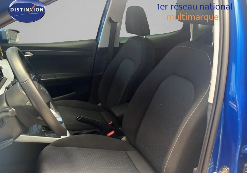 Vue intérieure côté conducteur du SEAT Arona bleu saphir, montrant les sièges avant en tissu noir et le volant cuir.