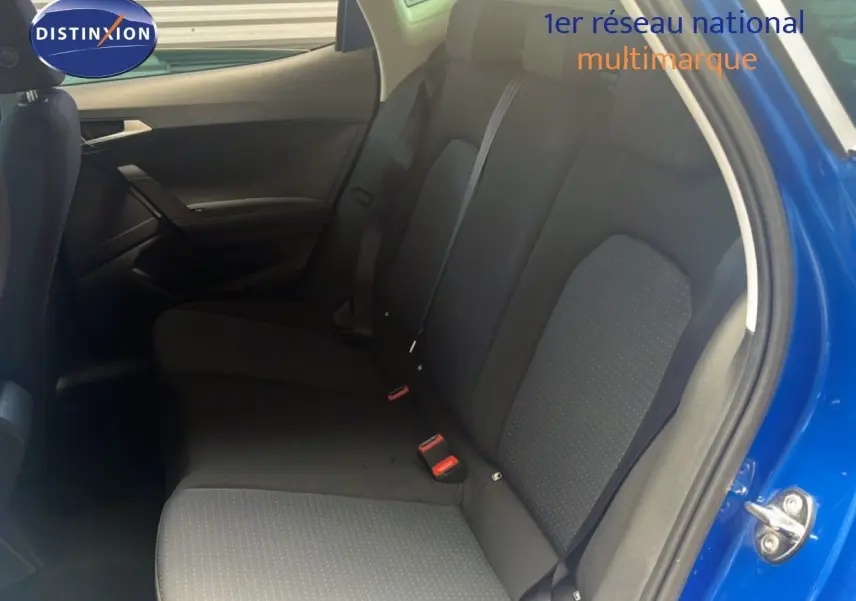 Vue intérieure arrière côté droit du SEAT Arona bleu saphir avec sièges tissu noirs et ceintures visibles.