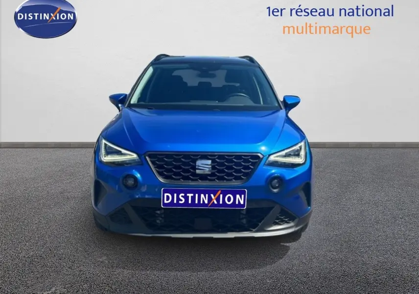 Vue avant d'un SEAT Arona bleu saphir métal avec toit noir, mettant en valeur ses phares LED et sa calandre distinctive.
