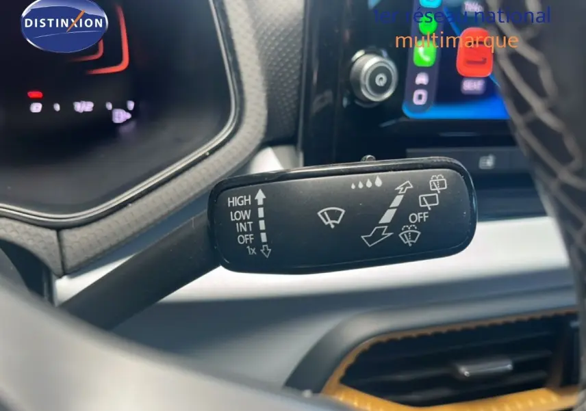 Gros plan sur la commande d’essuie-glace du SEAT Arona 2025, avec tableau de bord et écran tactile en arrière-plan.