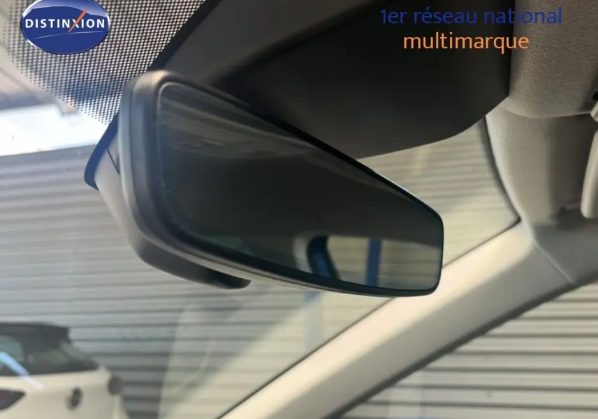 Rétroviseur intérieur en gros plan de la SEAT Arona bleu saphir métal avec toit noir, vue depuis l'habitacle côté conducteur.