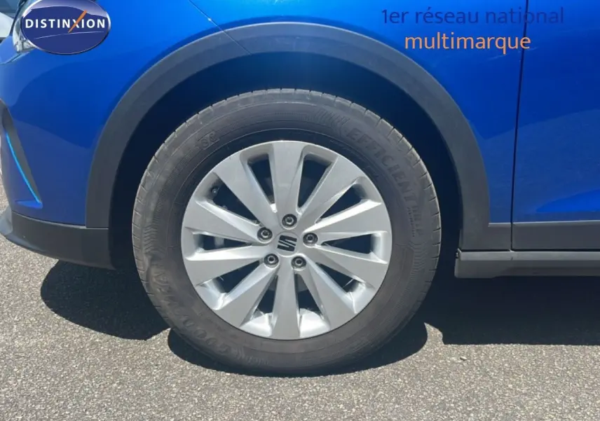 Gros plan sur la roue avant gauche d'une SEAT Arona bleu saphir avec jante argentée et passage de roue noir.