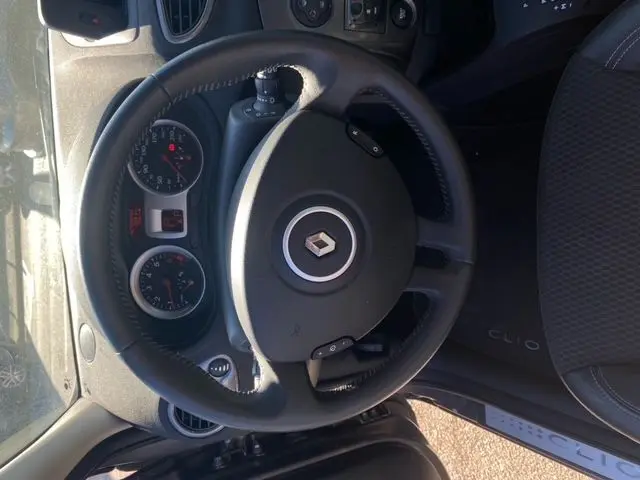 Vue intérieure de la Renault Clio III 110 ch exception tomtom 2010, montrant le volant et le siège conducteur côté gauche.