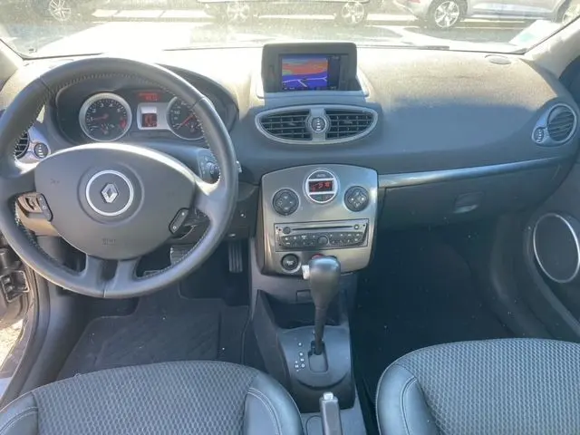 Vue intérieure avant de la Renault Clio III 110 ch exception tomtom 2010, tableau de bord gris avec écran GPS déployé au centre