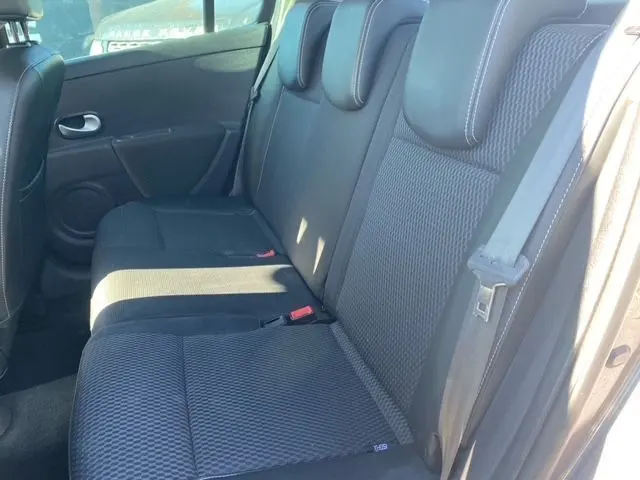 Vue latérale droite de l'intérieur arrière d'une Renault Clio III 2010, sièges tissu noir avec appuie-têtes intégrés.