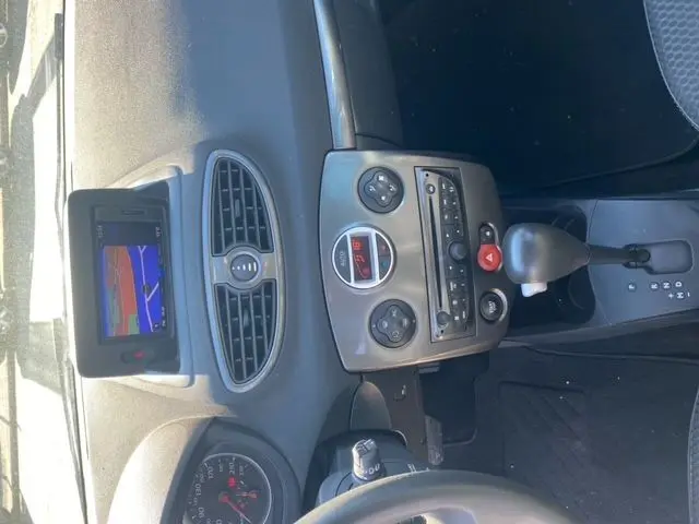 Vue intérieure du tableau de bord de la Renault Clio III 110 ch, avec GPS TomTom et commandes centrales visibles.