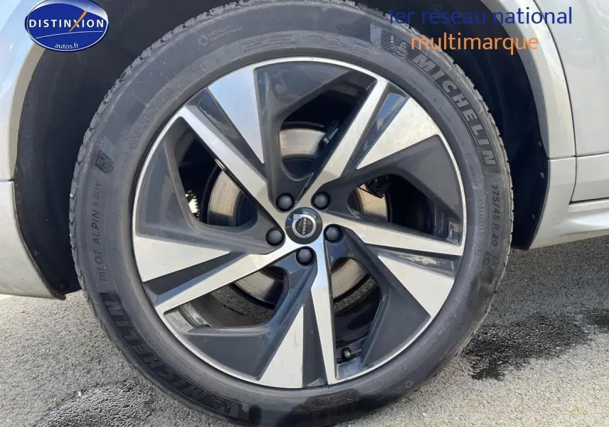 Gros plan sur la jante alu bicolore et pneu Michelin du côté arrière droit du Volvo XC90 gris.