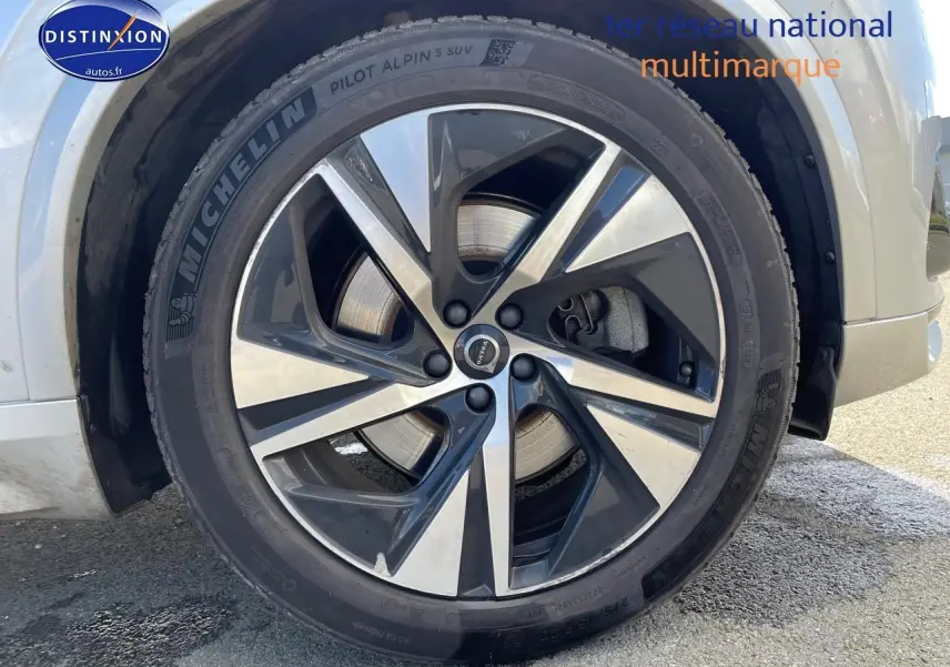Gros plan sur la jante alu bicolore et pneu Michelin d'un Volvo XC90 gris, côté avant droit.