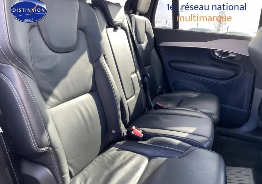 Vue latérale des sièges arrière en cuir noir du Volvo XC90 gris, avec accoudoirs et finitions élégantes sur la porte.