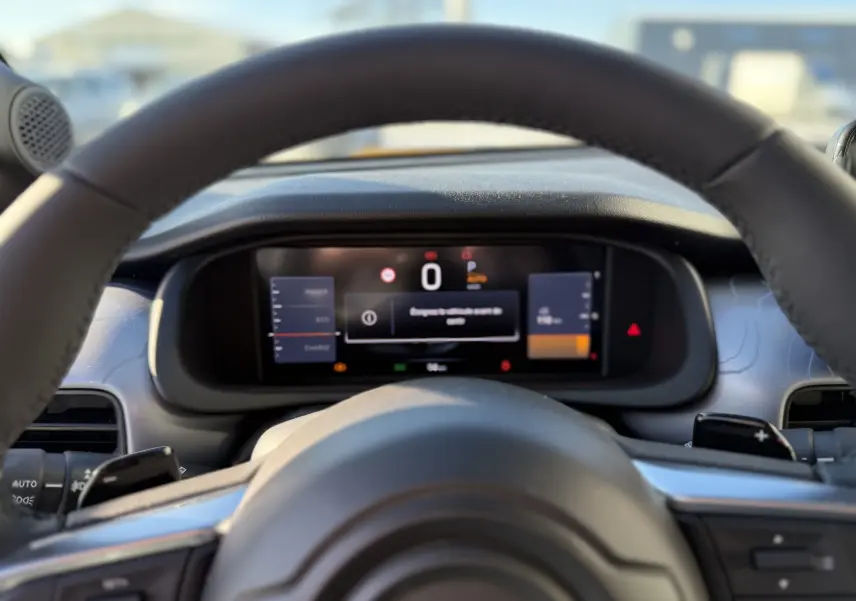 Vue intérieure centrée sur le tableau de bord numérique et le volant du Jeep Avenger gris Storm, version hybride 2025.