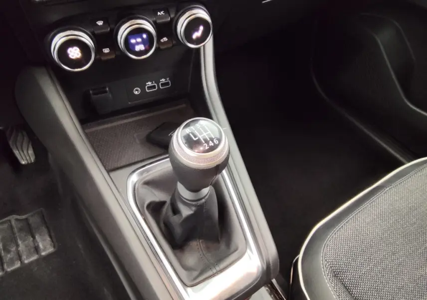 Gros plan sur la console centrale du Renault Captur 2024 gris cassiope, mettant en valeur le levier de vitesse manuel et les commandes de climatisation.