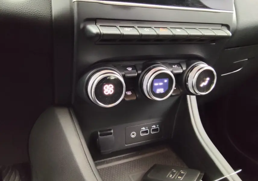 Gros plan sur les commandes de climatisation et les ports USB du tableau de bord intérieur du Renault Captur gris cassiope 2024.