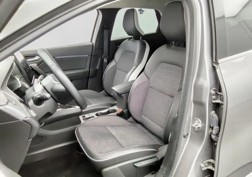 Vue intérieure côté conducteur de la Renault Captur 2024 gris cassiope avec sièges tissu et cuir noir, volant multifonction.