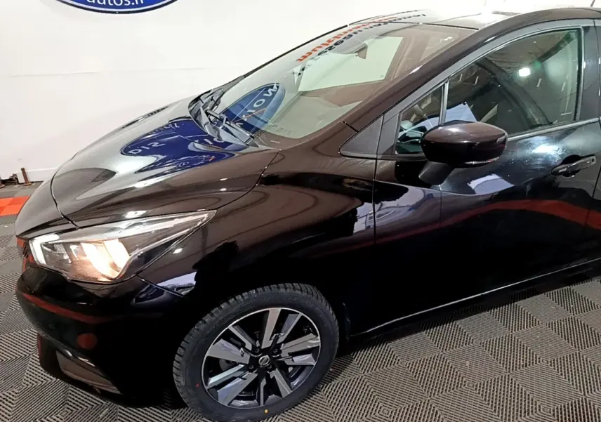 Vue 3/4 avant droit d'une Nissan Micra IG-T 90 N-Connecta noire, avec phares allumés et jantes alliage distinctives.