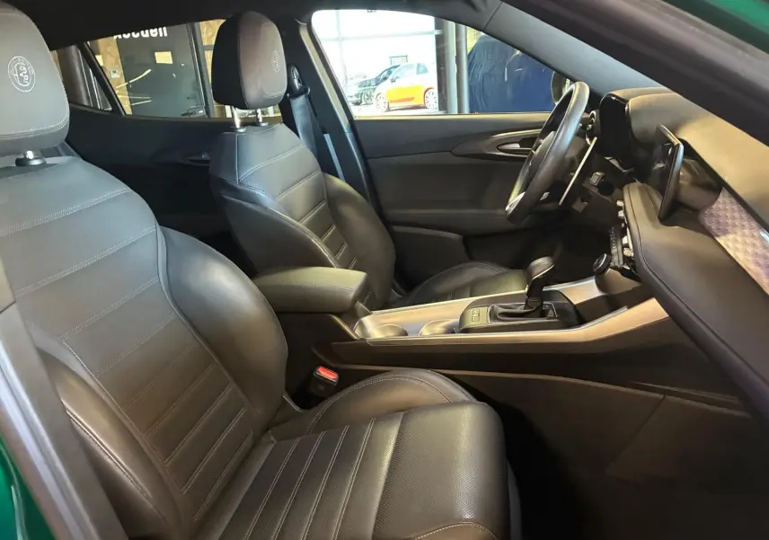 Vue intérieure côté conducteur de l'Alfa Romeo Tonale 2022, sièges cuir noir et console centrale avec levier de vitesse.