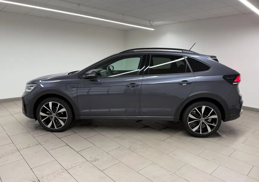 Vue de profil côté gauche du Volkswagen Taigo gris cendre avec jantes alliage 18 pouces en intérieur neutre.