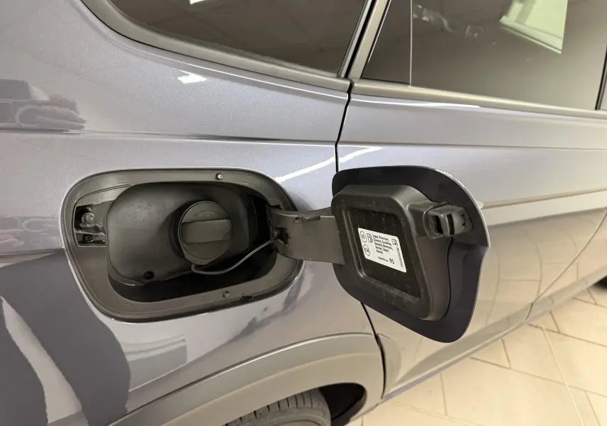 Vue latérale gauche du Volkswagen Taigo gris cendre, avec trappe à carburant essence ouverte et bouchon visible.