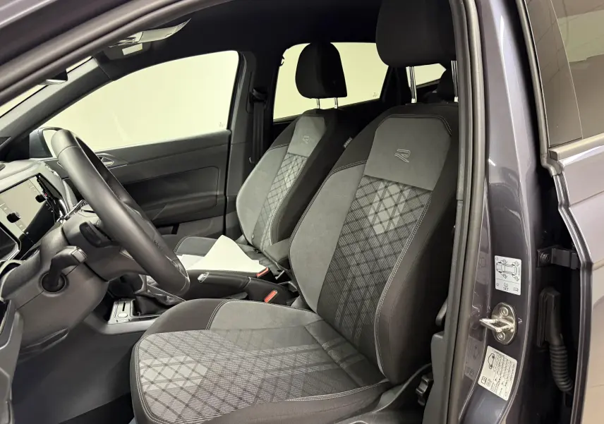 Vue intérieure côté conducteur du Volkswagen Taigo gris cendre, sièges sport avec logo R brodé et volant cuir multifonctions.