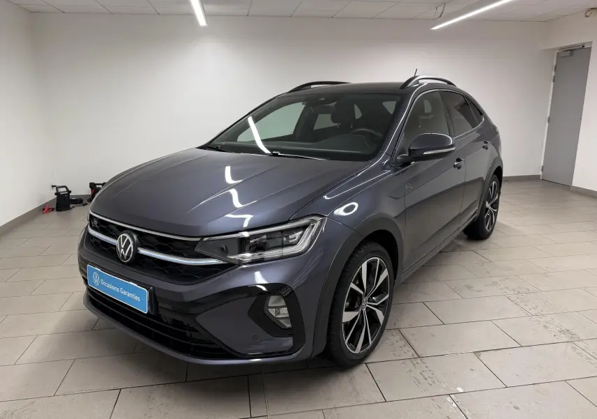 Volkswagen Taigo gris cendre en 3/4 avant droit, avec jantes alliage 18'' et calandre R-Line visible.