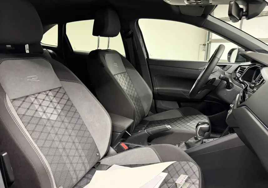 Vue intérieure côté conducteur du Volkswagen Taigo R-Line avec sièges sport gris à motifs géométriques et volant multifonctions.