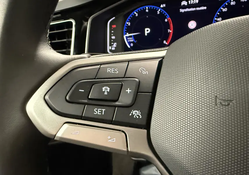 Gros plan sur les commandes au volant cuir noir du Volkswagen Taigo 1.0 TSI 116 DSG7 R-Line Edition, avec tableau de bord digital.