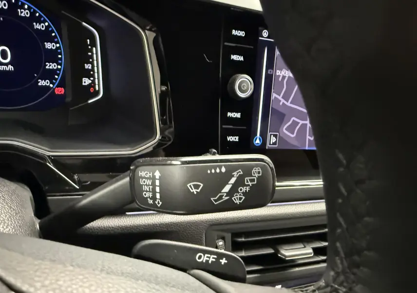 Gros plan intérieur sur la commande d’essuie-glace et le tableau de bord numérique du Volkswagen Taigo gris cendre.