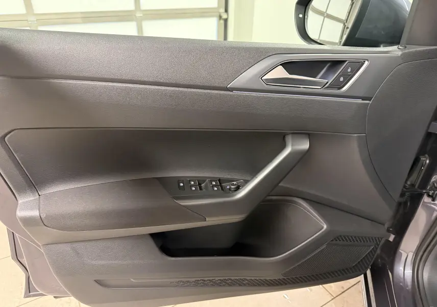 Vue intérieure côté gauche de la porte avant d'un Volkswagen Taigo gris cendre avec commandes électriques et poignée intégrée.