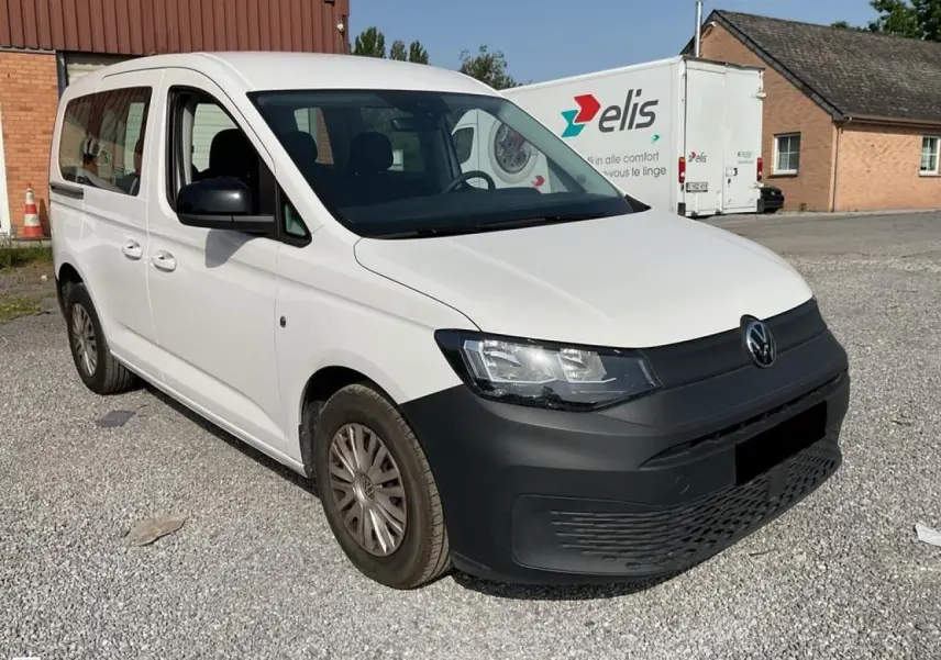 Volkswagen Caddy blanc Candy vue 3/4 avant droit avec pare-chocs noir mat et jantes acier.