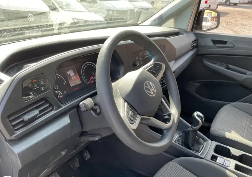 Intérieur de Volkswagen Caddy blanc Candy 2024, vue côté conducteur sur le volant multifonctions et la boîte manuelle.