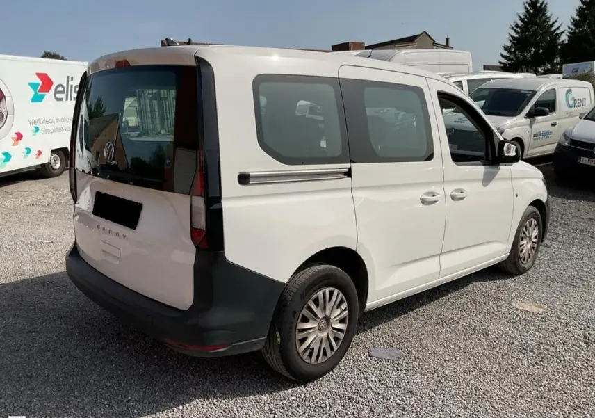 Vue 3/4 arrière droite d'un Volkswagen Caddy blanc Candy 2024 avec portes coulissantes et hayon vitré.
