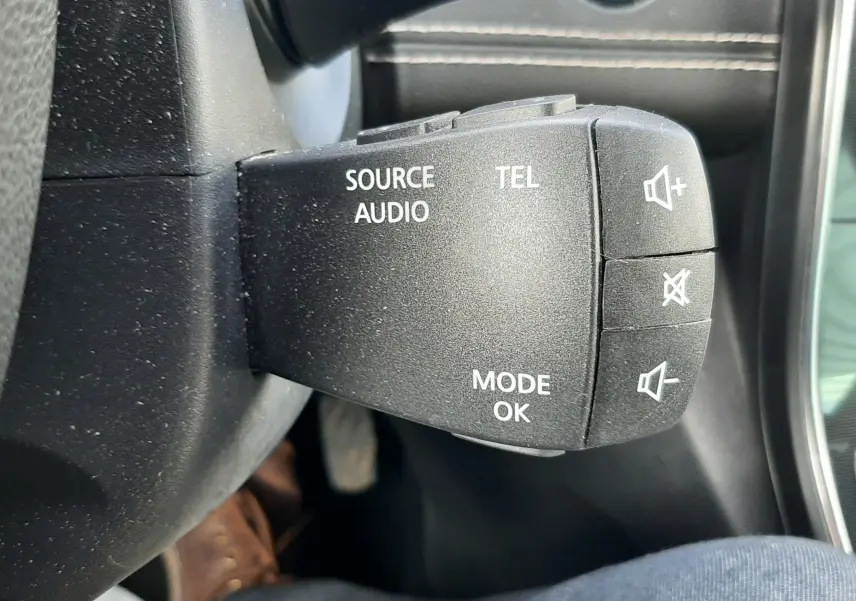 Gros plan sur les commandes multifonctions noires à droite du volant en cuir noir du Renault Scenic IV gris Cassiopée.